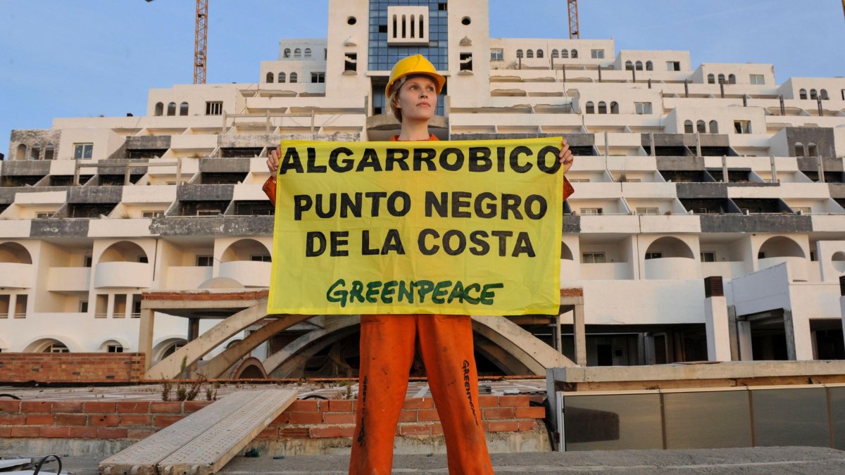 Una activista de Greenpeace porta una pancarta de protesta frente al hotel de El Algarrobico.