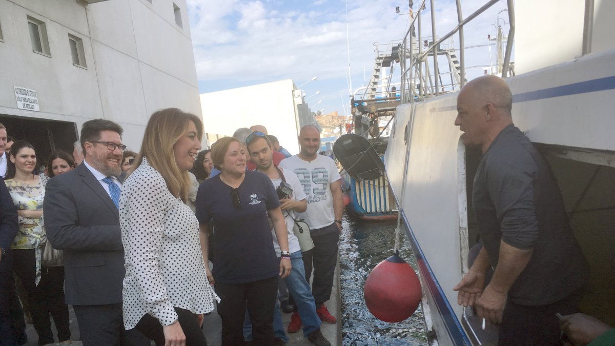 Susana Díaz y un pescador se saludan con el mar y las boyas de por medio en la tarde de ayer.