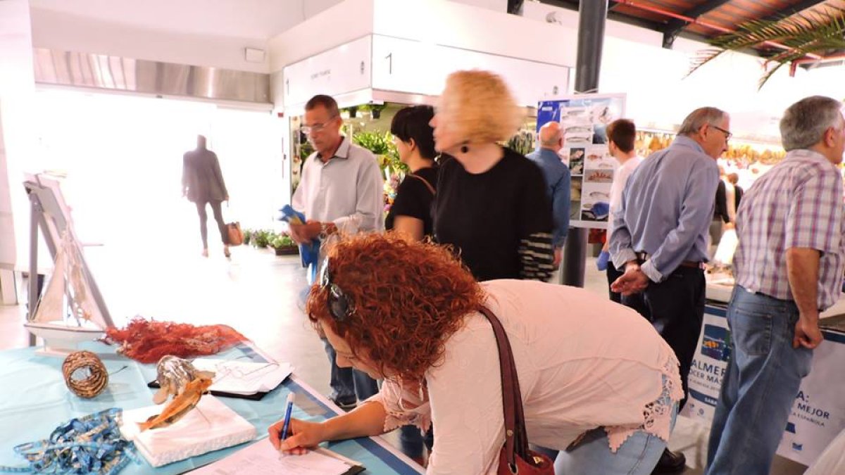 Una mujer firma el manifiesto de defensa de la pesca de arrastre en el Mercado.