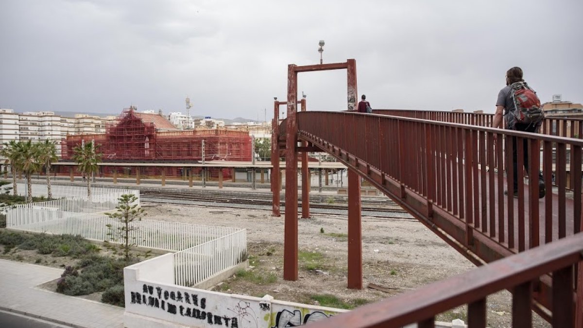 La antigua estación de tren, en obras, y el puente rojo que permite cruzar sobre las vías.