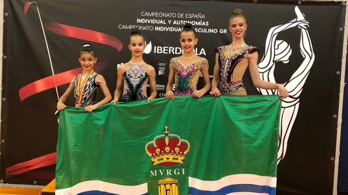 Las campeonas posan con la bandera del municipio.
