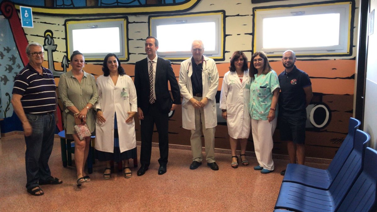 Delegado y profesionales en la sala de espera de Pediatría con el mural de Luis Javier Martínez.