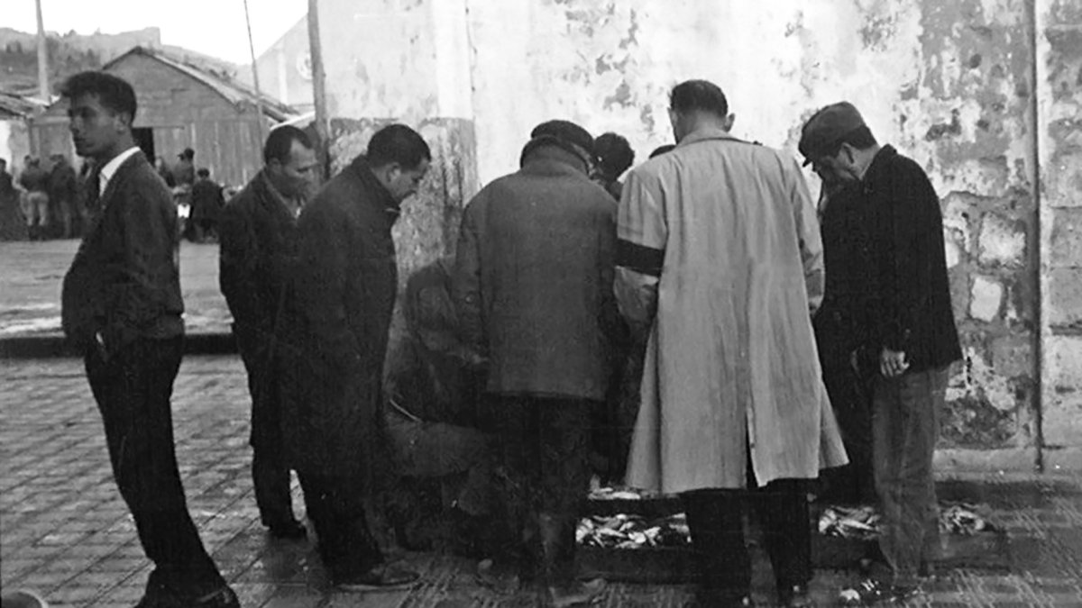 Un grupo de hombres se disputa unas cajas de pescado en el muelle pesquero.