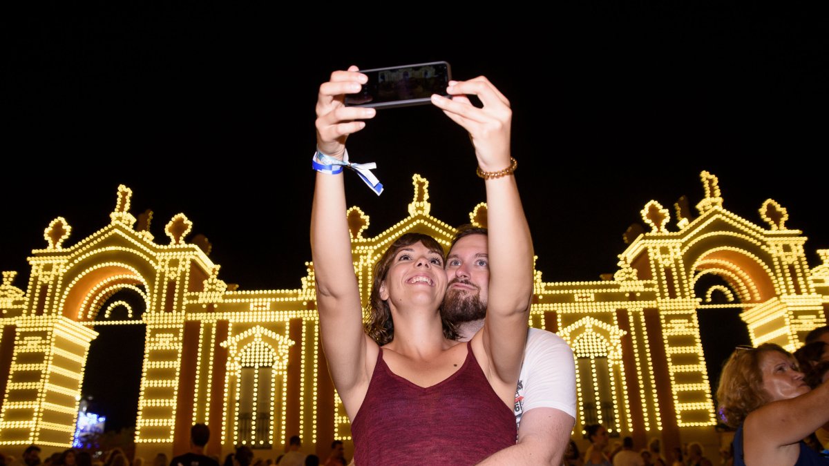 Una pareja se hace un selfi frente a la portada del Recinto Ferial.