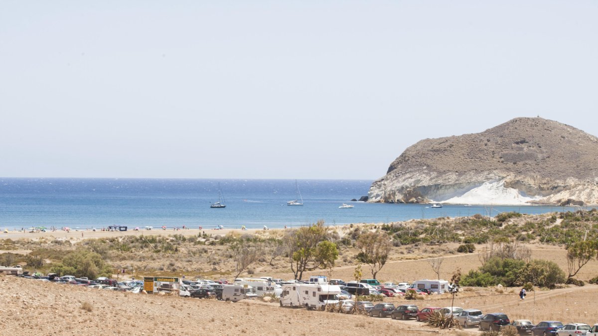 Camino de acceso al aparcamiento de Genoveses, con vehículos en los lados.