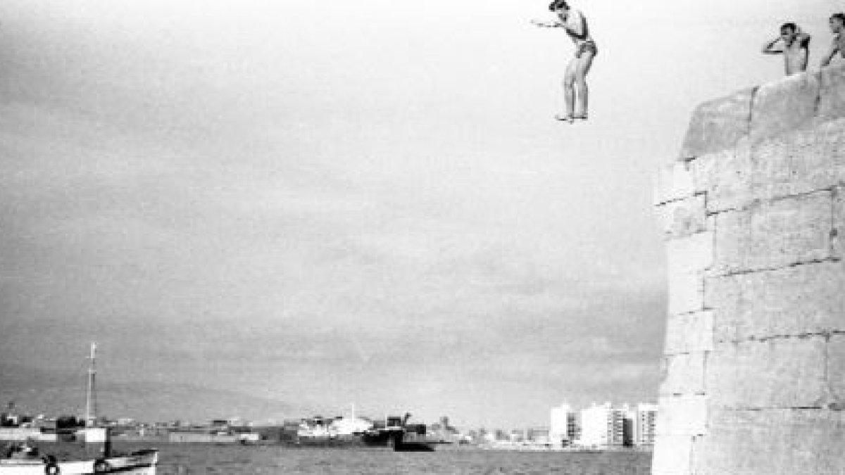 Un grupo de jóvenes lanzándose al mar desde las piedras del fortín del Faro.