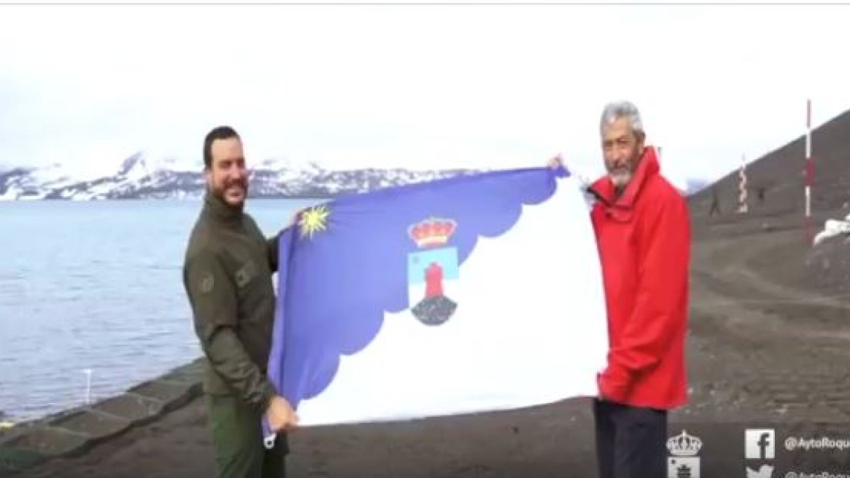 Los dos almerienses portando la bandera de Roquetas en la Antártida.