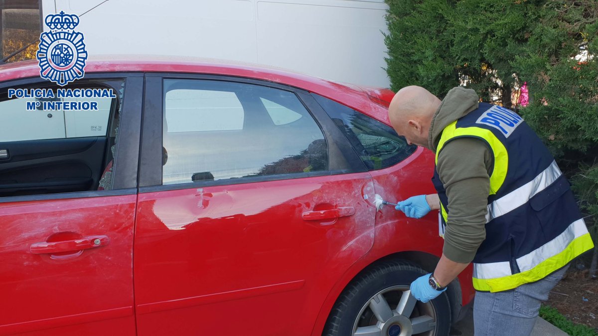 Un agente buscando huella en el exterior de un vehículo.
