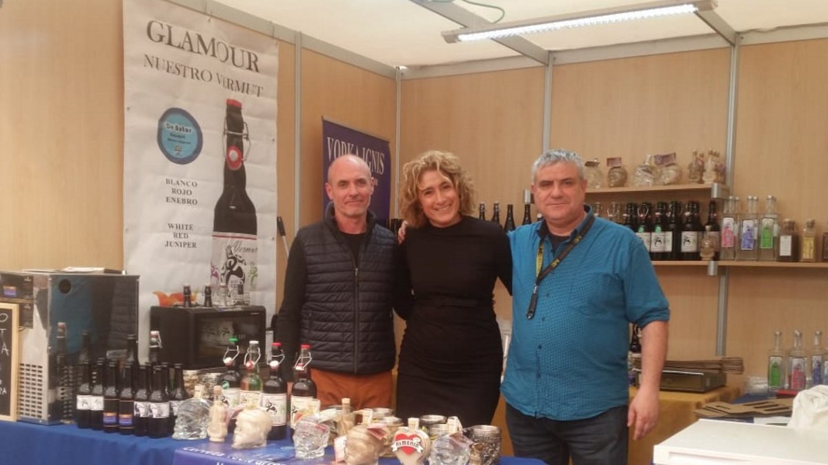 José Antonio Moya (a la derecha) junto a dos colaboradores en un stand de degustación, Al lado, un cartel de su vermut.
