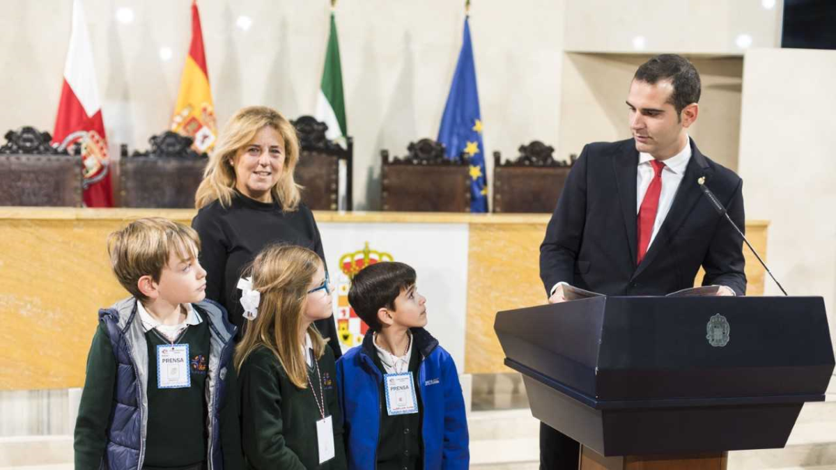 tres jóvenes escolares observan con atención al alcalde