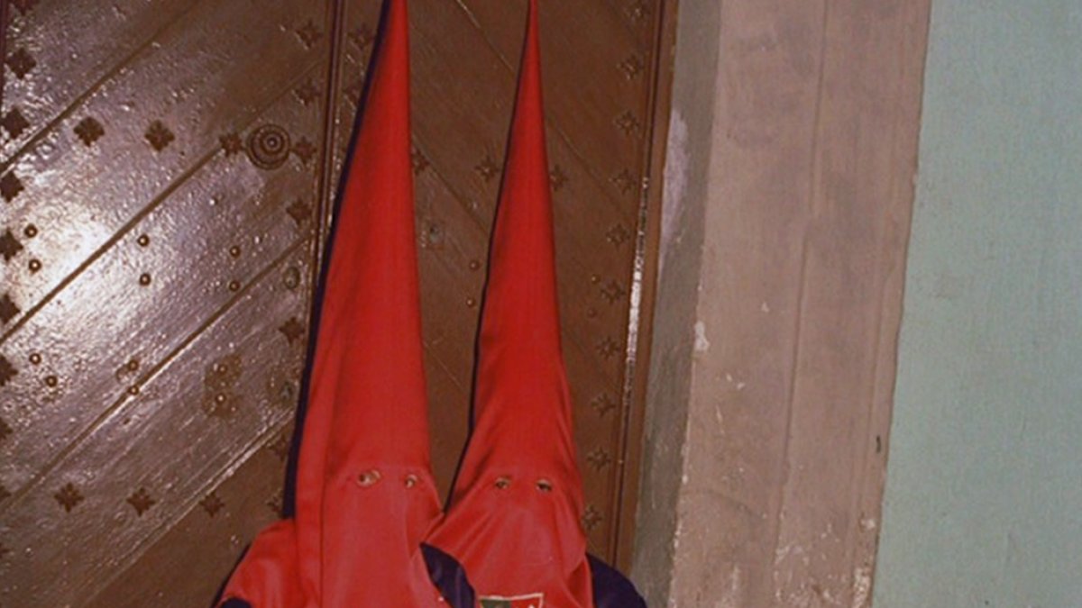 En la foto, dos penientes de la cofradía de Estudianates sentados en un tranco.