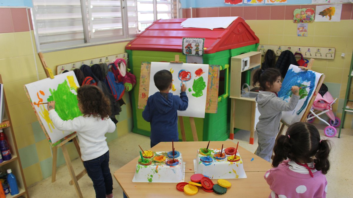 Alumnos realizando pinturas según su creatividad en tres lienzos mientras otra alumna aguarda su turno.