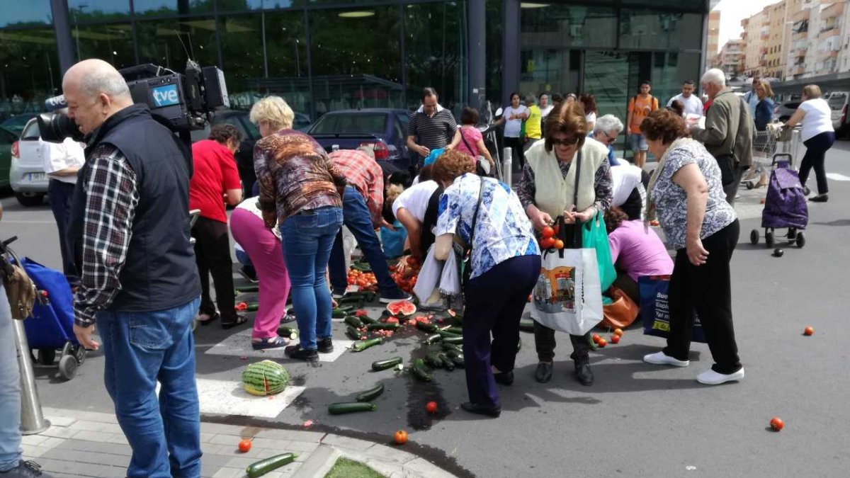 Almerienses cogiendo las verduras arrojadas frente al supermercado.
