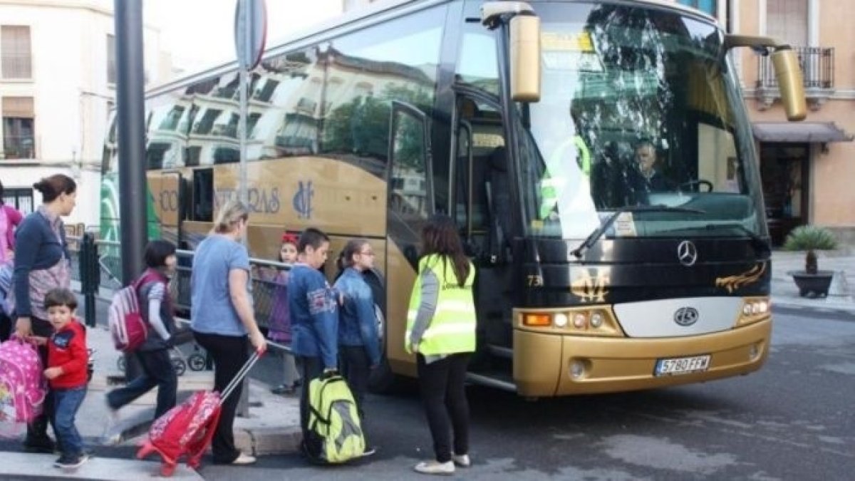 Estudiantes entran en un autobús de transporte escolar.