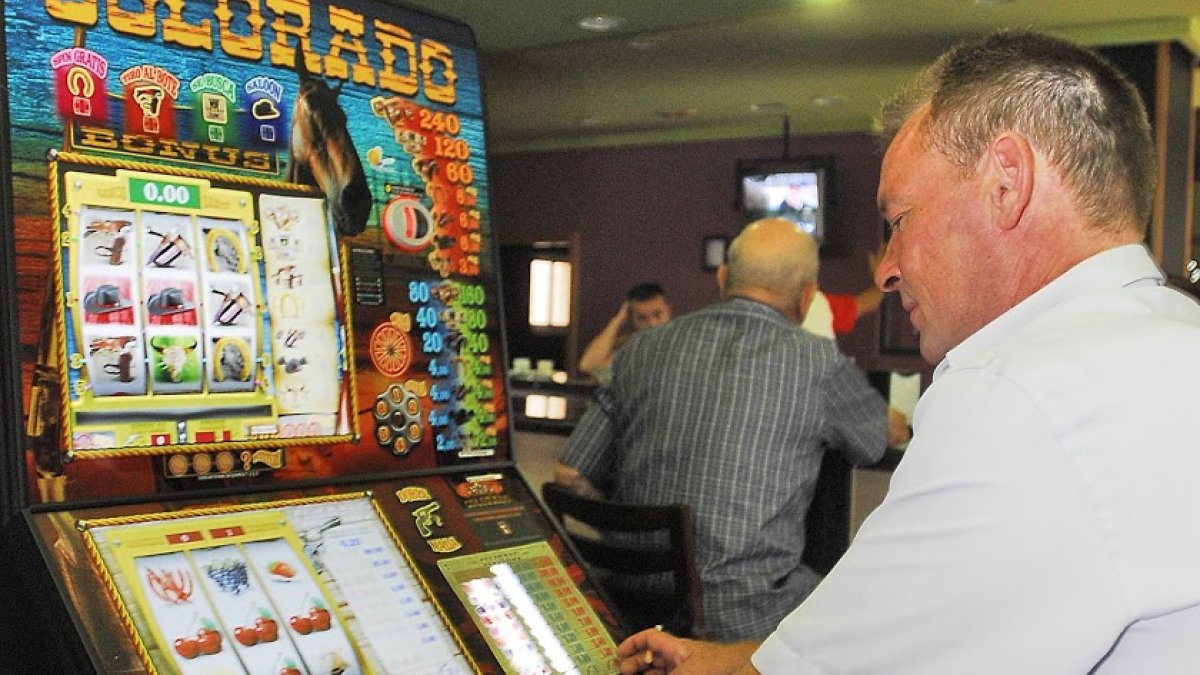 Un hombre juega a la máquina tragaperras en un salón de juego.