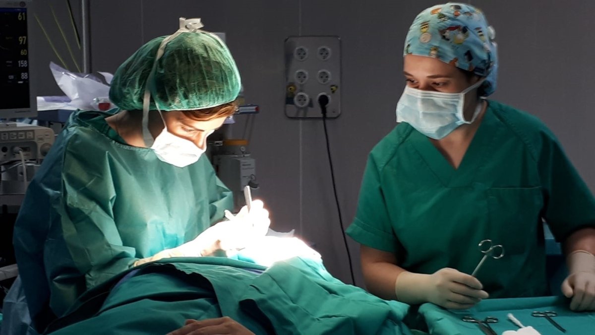 Dos facultativos practican una intervención quirúrgica.