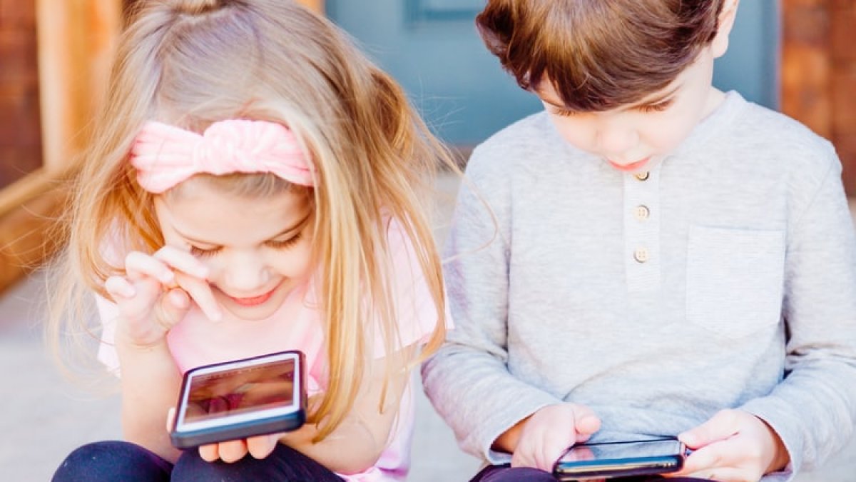 Dos niños pequeños juegan con el móvil de sus padres.