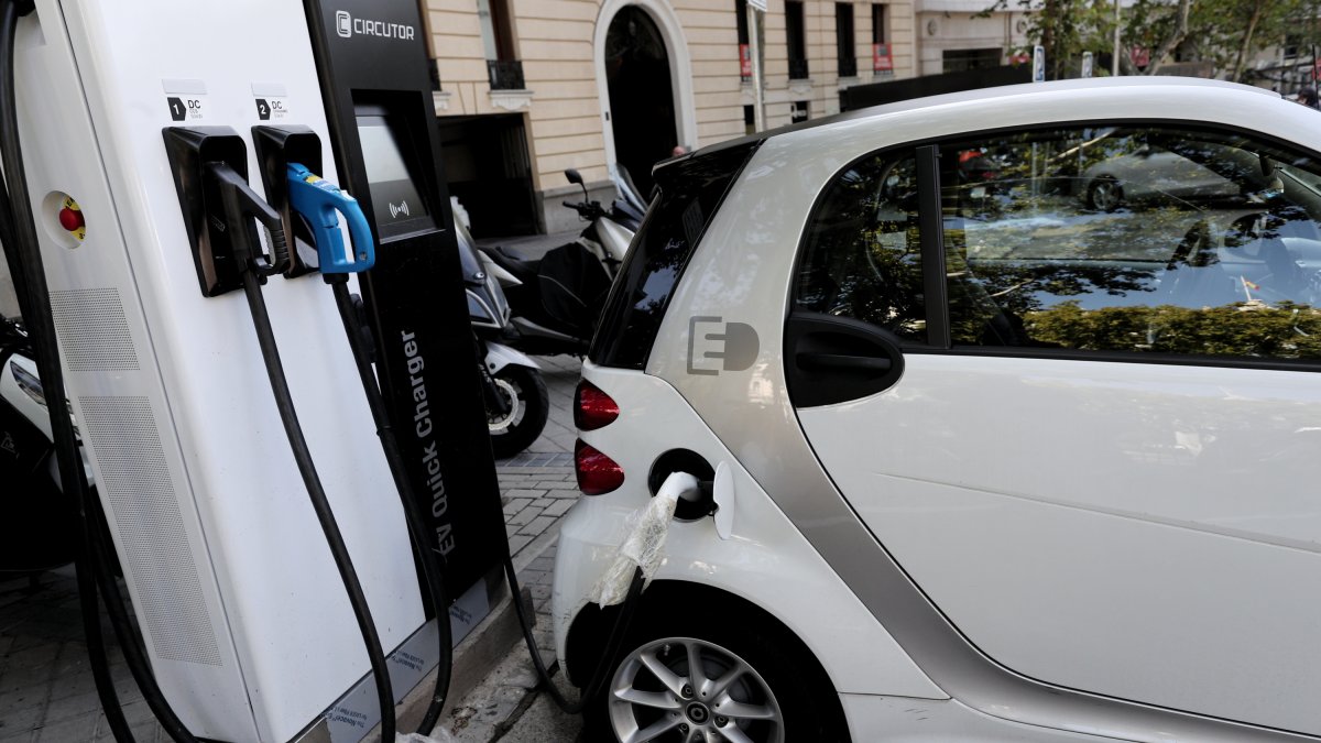 Imagen de un vehículo híbrido mientras procede a cargarse en un punto de recarga de batería.