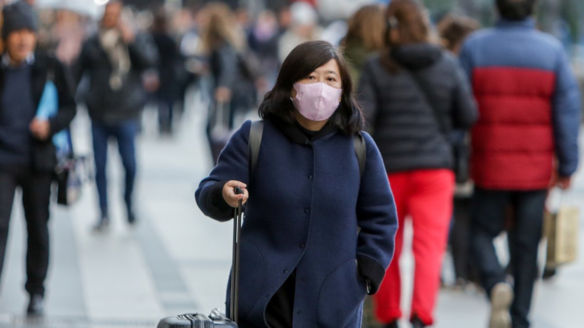 Una mujer de origen asiático camina con una mascarilla por las calles de Madrid.