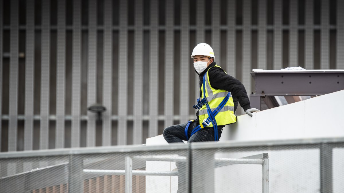 Un trabajador asiático con mascarilla en el exterior del pabellón del Mobile World Congress.