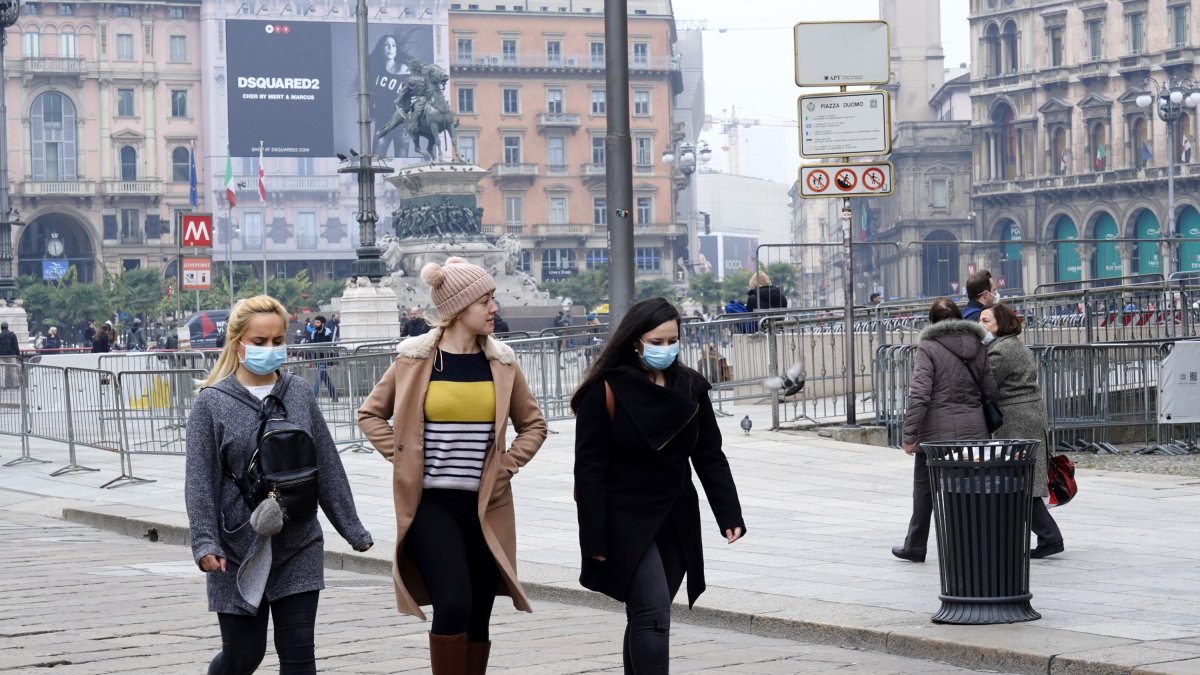 Tres jóvenes caminan por Milán, dos de ellas con mascarillas.