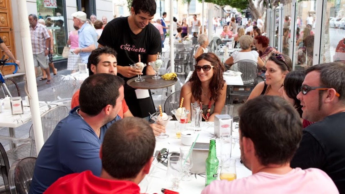 Un camarero sirviendo a varios clientes en el Paseo de Almería.