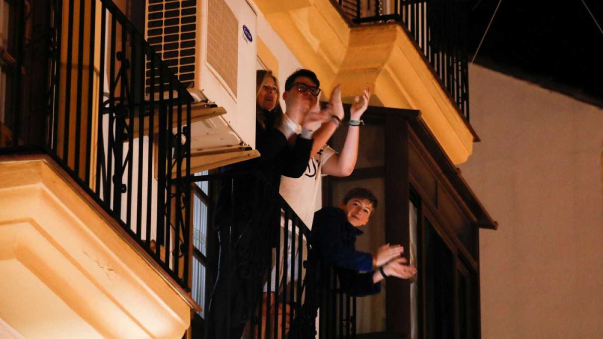 Una familia aplaudiendo ayer desde el balcón, que ha pasado a ser el catalejo desde el que se avizora la poca vida del exterior.