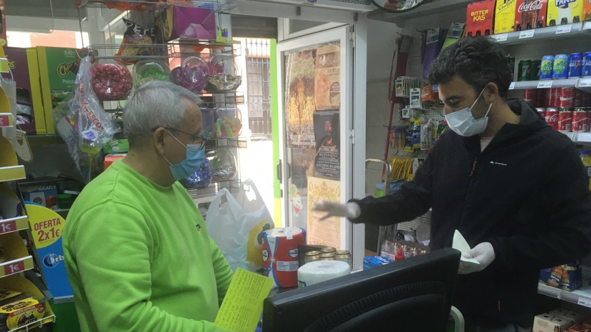 José Antonio Carreño con un cliente, en el supermercado que regenta en la calle La Reina