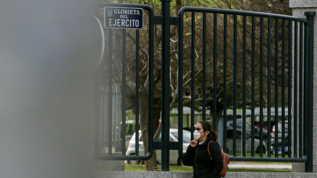 Una mujer pasea con mascarilla por una vía pública.