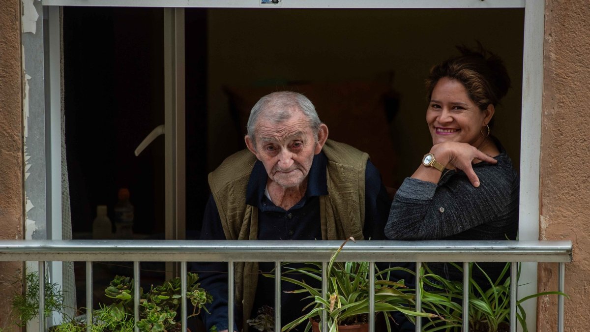 Miguel mira a su enamorada desde su balcón, en compañía de Petrona, su cuidadora.