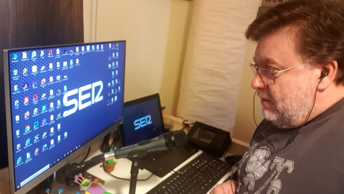 El periodista Alfredo Casas , con buen aspecto, haciendo el programa de radio de la Cadena Ser desde su casa, con juguetes en la mesa.