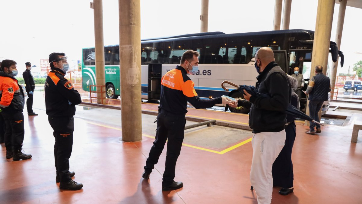 Imagen de un agente de protección civil entregando una mascarilla a un pasajero.