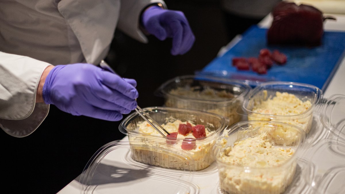 Un cocinero prepara un plato para llevar en un restaurante.
