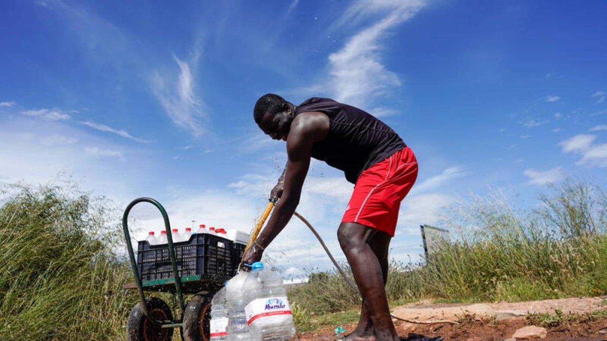 Un inmigrante haciendo acopio de agua en el campo.