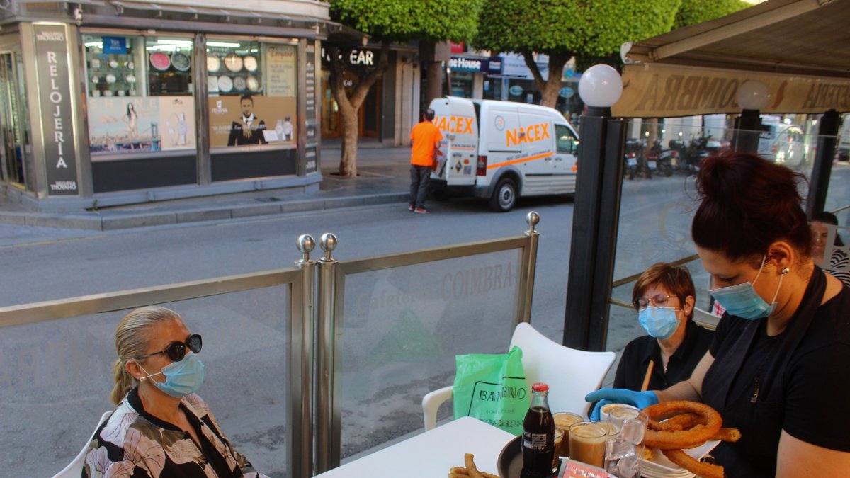Una camarera atiende a dos clientas en una terraza del Paseo de Almería.