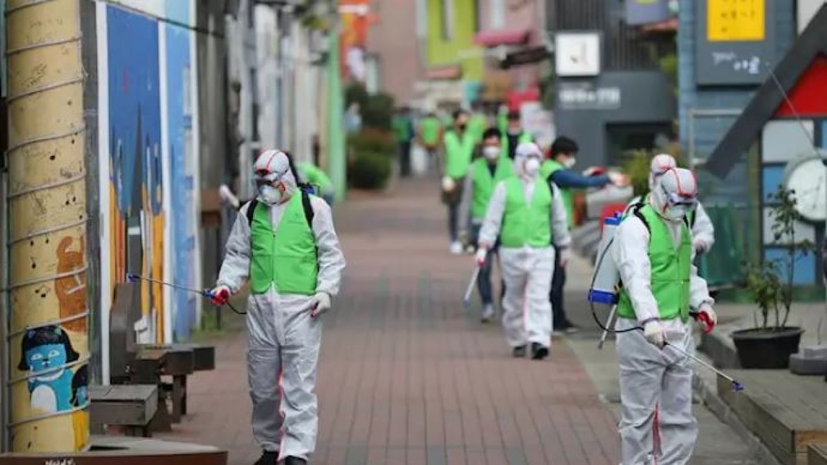 Un grupo de trabajadores desinfectan una calle de Corea del Sur.