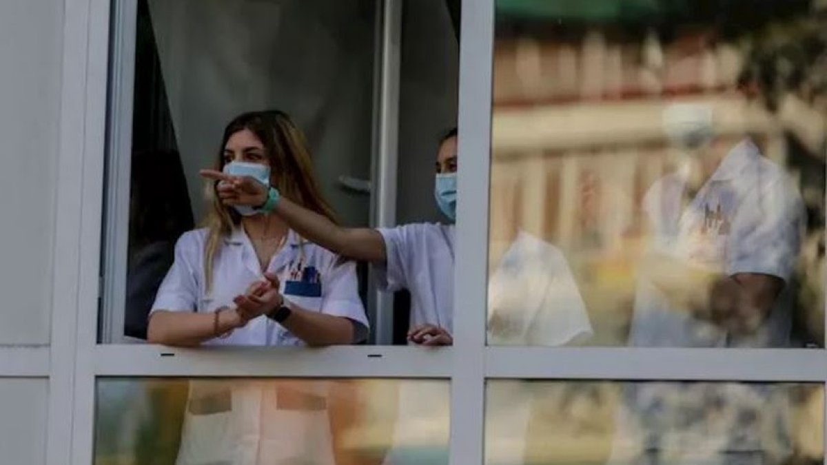 Sanitarios asomados a la ventana de un hospital.