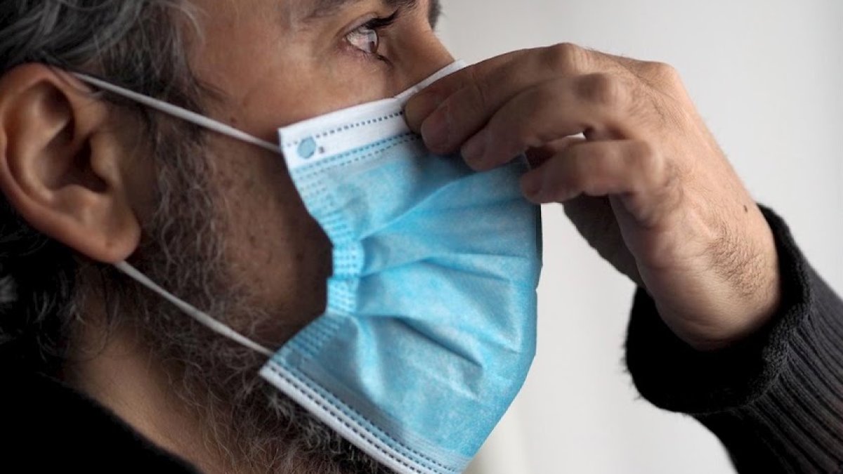 Un hombre se pone una mascarilla.