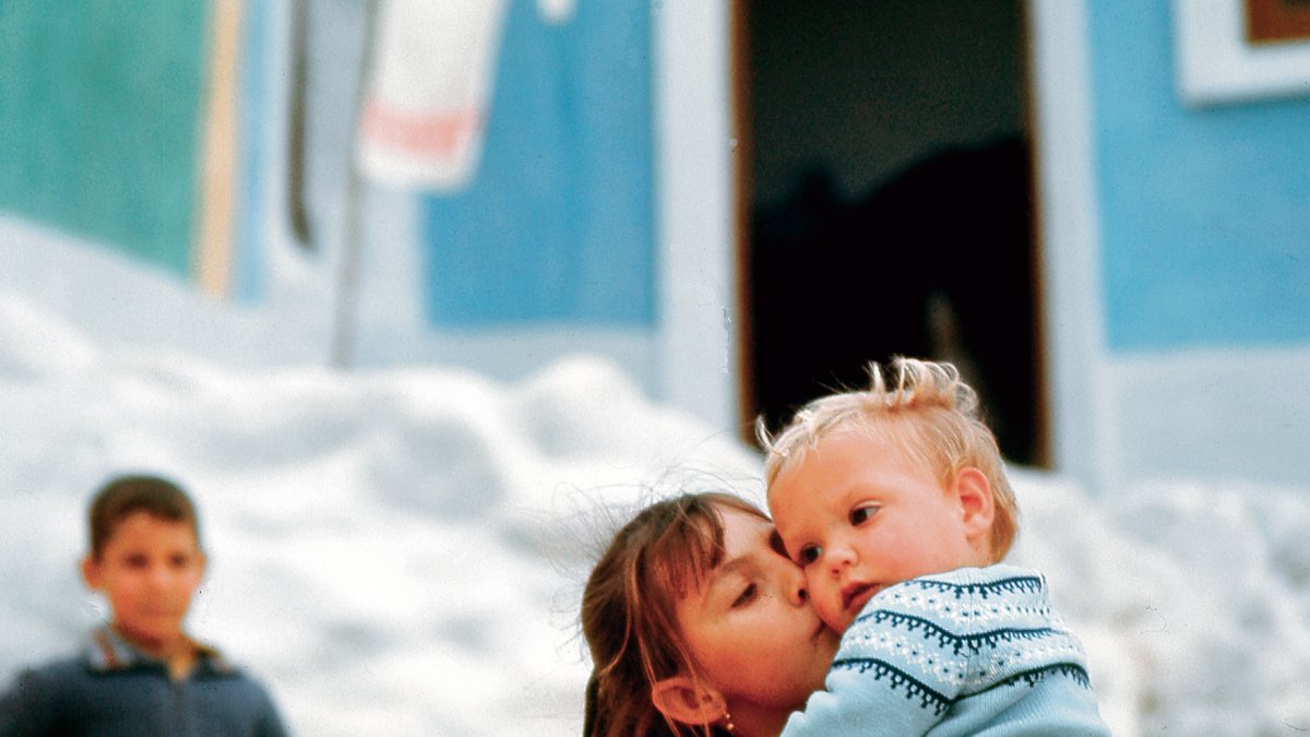 Una niña del barrio de las cuevas de la Alcazaba llevando en brazos y besando a su hermano pequeño.