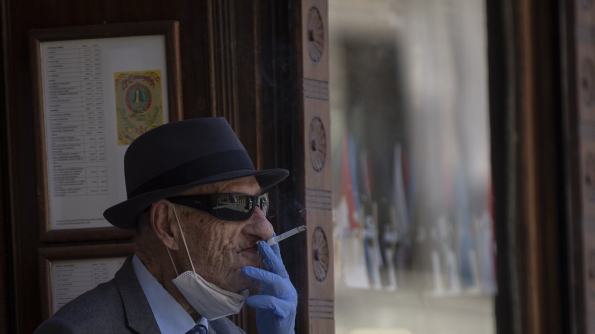 Un hombre con mascarilla y guantes fumando un cigarro en Sevilla.
