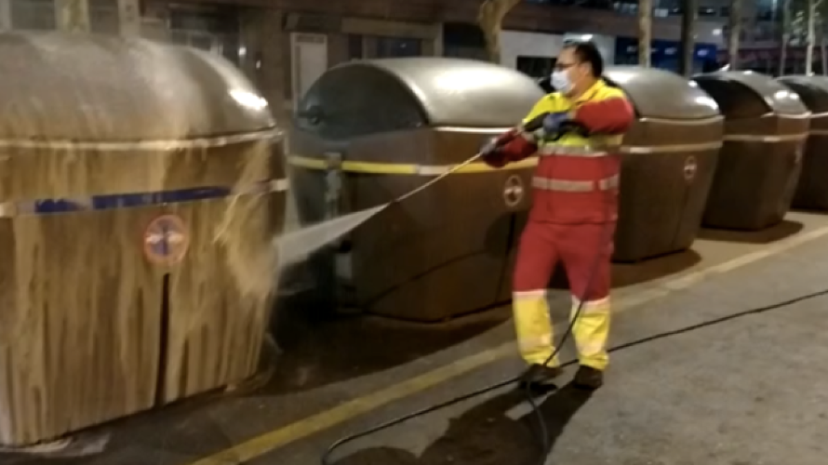 Un trabajador limpia un contenedor.