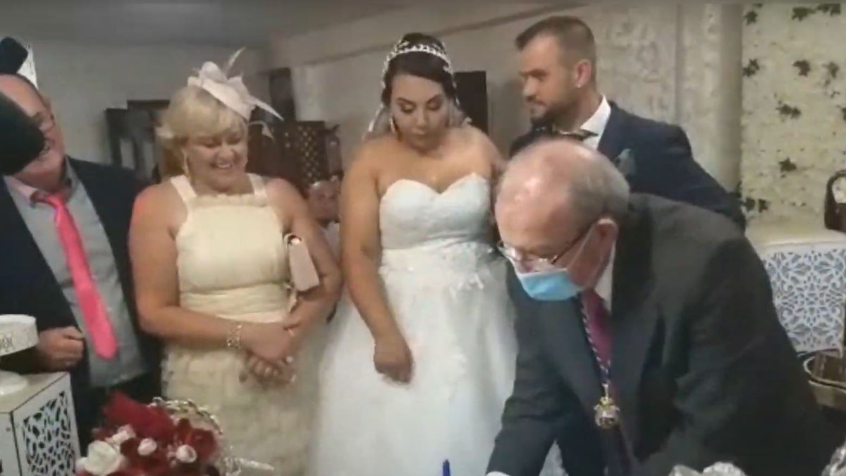 Bonilla firmando en presencia de los novios y otras personas sin mascarillas.