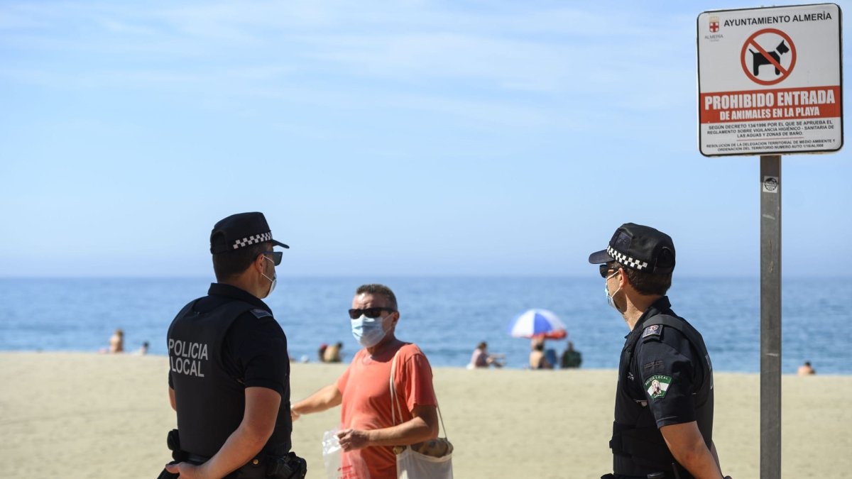 Un almeriense, con la mascarilla obligatoria puesta, dialoga con la Policía Local, que controla su uso.