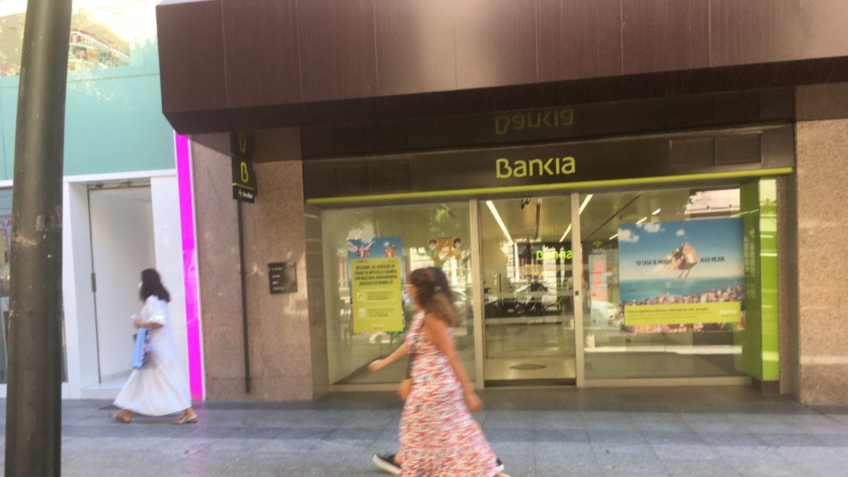 Transeúntes  caminando ayer por el Paseo de Almería junto a la oficina central de Bankia, tras conocerse los contactos con CaixaBank.