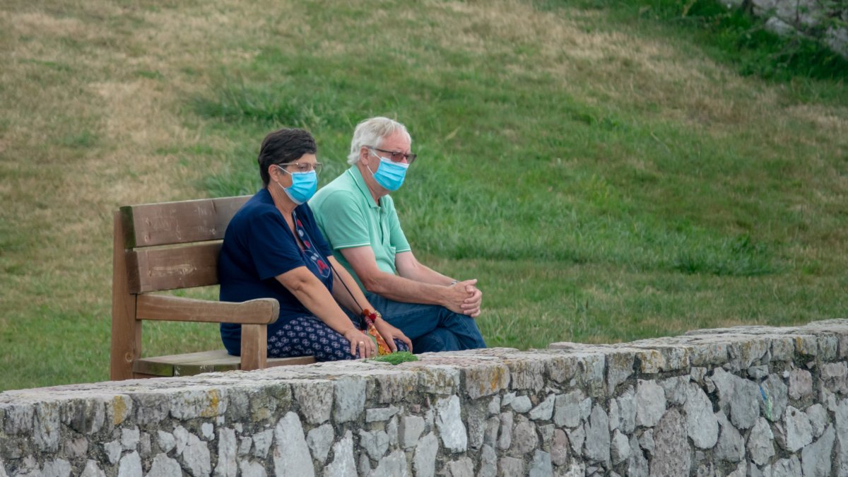 Imagen de archivo de una pareja sentada con mascarillas.