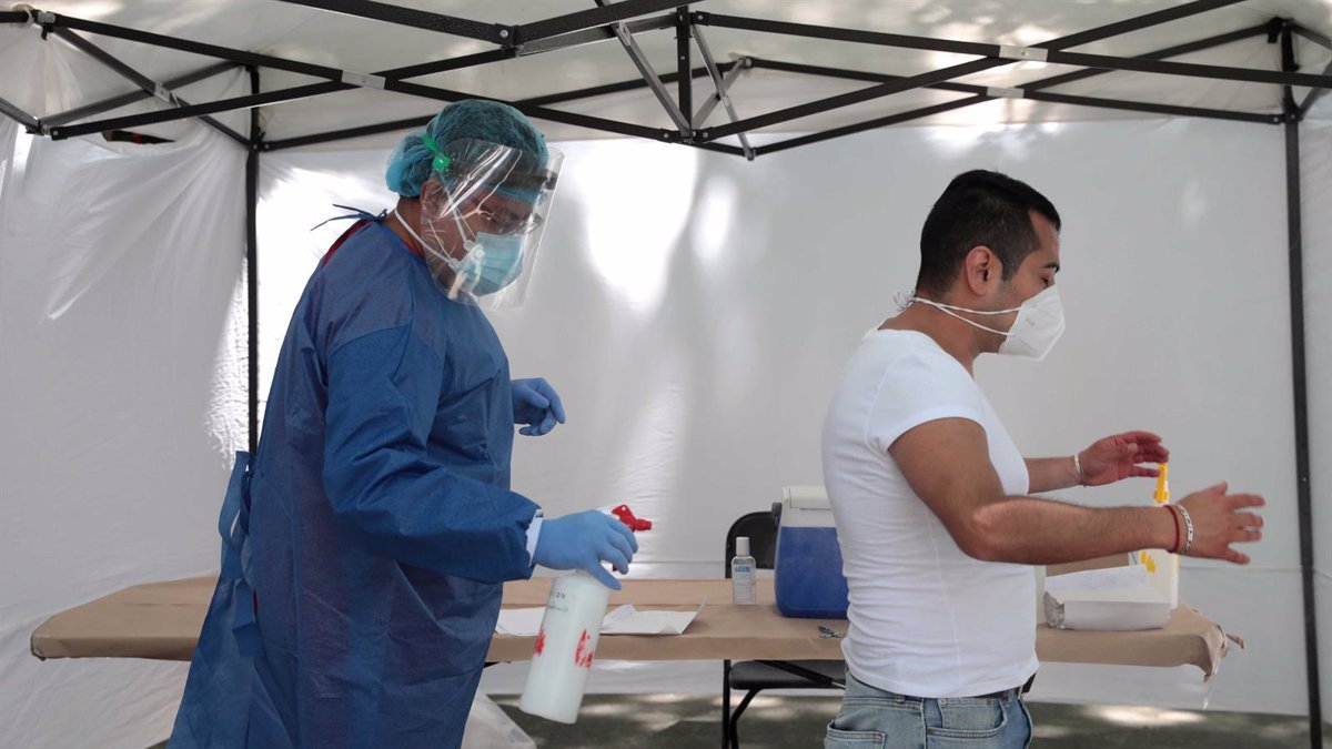 Sanitarios desinfectan a un paciente que va a someterse a una PCR.