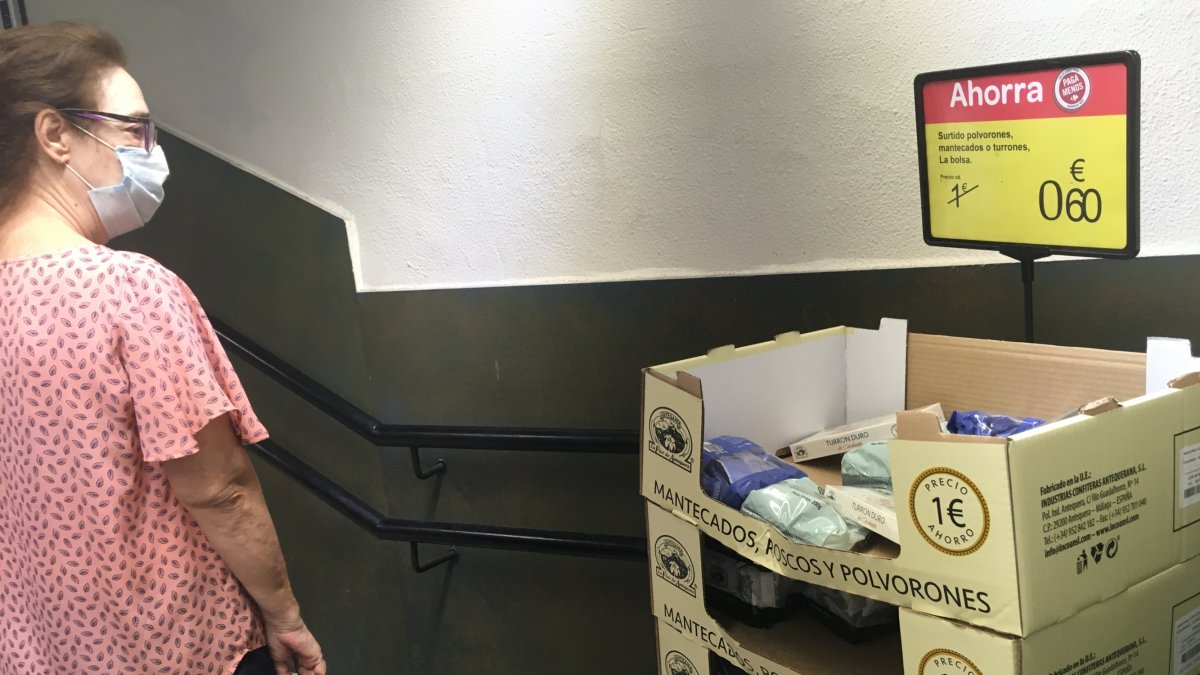 Una señora mira las cajas de polvorones en un supermercado del centro.