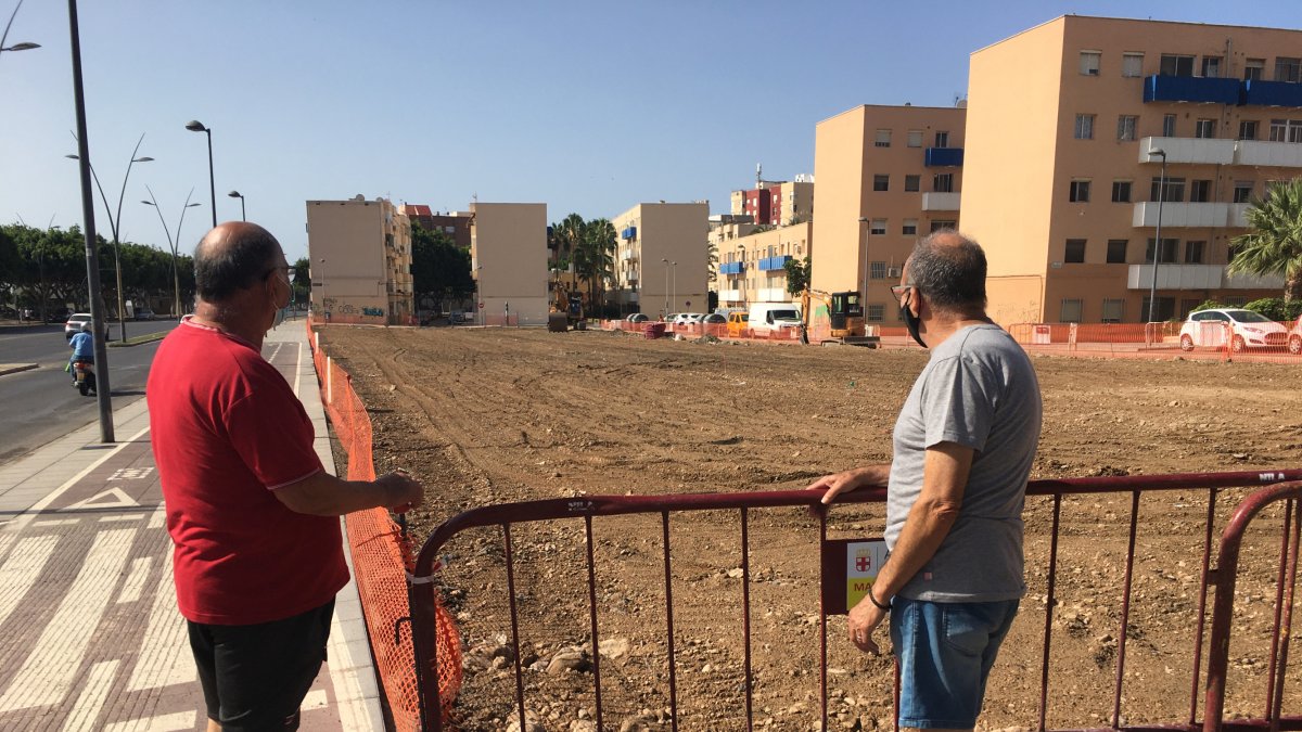 Dos almerienses miran unas obras junto a la Avenida del Mediterráneo este pasado verano.