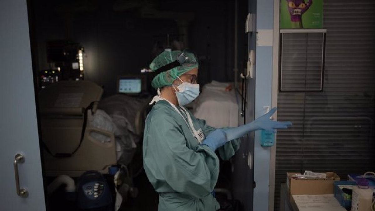Una sanitaria se pone unos guantes en la Unidad de Cuidados Intensivos.