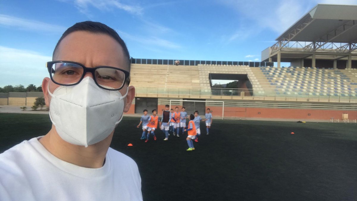 El entrenador en primer plano y sus futbolistas de fondo.